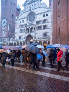 Cremona, Italy - February 9th 2025 Faithful catholics holding umbrellas during a procession in front of Santa Maria Assunta Cathedral in Cremona, Italy, on a rainy day clipart