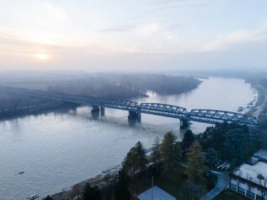 Cremona, İtalya - 9 Şubat 2025 İtalya, Cremona 'da Po Nehri' nin havadan görünüşü, sakin bir kış günbatımını Lombardy ile Emilia Romagna arasında uzanan bir köprüyle sergiliyor.