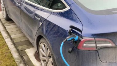 Cremona, İtalya 9 Şubat 2025 Mavi Tesla model 3, Cremona, İtalya 'daki elektrikli araç şarj istasyonunda, arabanın farklı açılarını gösterirken şarj oluyor.