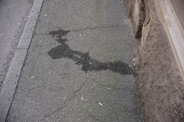 Cremona, İtalya 9 Şubat 2025 'te hasarlı bir duvarın yanında asfalt lekeli koyu renkli motor yağı, İtalya' nın Cremona kentindeki bozulmayı vurguluyor. Kirli doku ve kirlilik aşikar