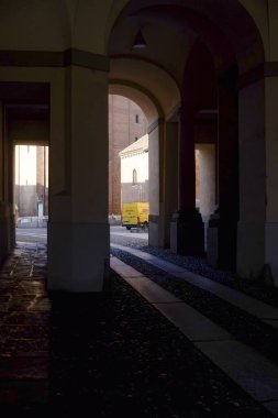 Cremona, İtalya 9 Şubat 2025 Sarı DHL minibüs arka planda bir kilise ve tuğla bina ile Alessandria, İtalya 'da kemer altı avludan ayrılıyor
