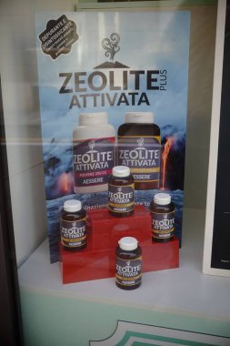 Cremona, İtalya 9 Şubat 2025 Zeolite Plus Attivata şişeleri vitrindeki kırmızı bir stantta sergilenerek, tanıtım afişinde bu sağlık ilavesinin faydalarını vurguladı.