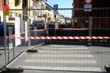 Cremona, İtalya 9 Şubat 2025. Kırmızı ve beyaz şeritli şerit metal bir çitin etrafına sarılmış ve yol bakımı sırasında bir yaya geçidini engelliyor.
