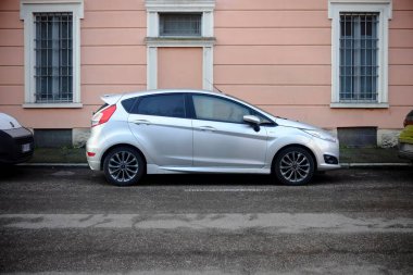 Cremona, İtalya 9 Şubat 2025 Bir gümüş Ford Fiesta sokağın kenarına park etmiş, Pembe pencereli bir binanın önünde
