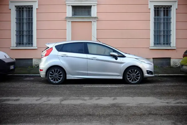 Cremona, İtalya 9 Şubat 2025 Bir gümüş Ford Fiesta sokağın kenarına park etmiş, Pembe pencereli bir binanın önünde