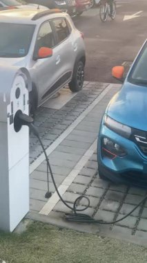 Cremona, İtalya 9 Şubat 2025 Cremona, İtalya 'da kamu şarj istasyonunda çalışan Mavi Koltuklu elektrikli araba, bir Tesla' nın yanına park edilmiş, sürdürülebilir ulaşım çözümleri sergiliyor.