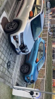 Cremona, İtalya 9 Şubat 2025 Cremona, İtalya 'da kamu şarj istasyonunda çalışan Mavi Koltuklu elektrikli araba, bir Tesla' nın yanına park edilmiş, sürdürülebilir ulaşım çözümleri sergiliyor.