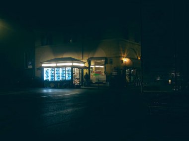 Cremona, İtalya 15 Kasım 2021 'de Cremona, İtalya' da bir sokak köşesinde gece, karanlık çevreyle çelişen parlak ışıklı bir otomat duruyor.