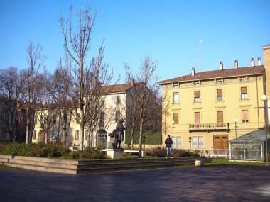 Cremona, İtalya 15 Kasım 2021 İtalya, Cremona, İtalya 'da bulunan Piazza Filopanti' de güneşli bir kış gününde Antonio Stradivari 'nin heykeline hayran kalan genç bir adam.