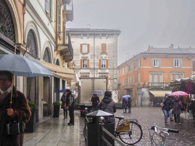 Cremona, İtalya 15 Kasım 2021 İtalya Cremona, İtalya 'nın kaldırım taşı caddeleri boyunca şemsiyelerle yürüyen insanlar nemli ve bulutlu bir günde yol alıyorlar.