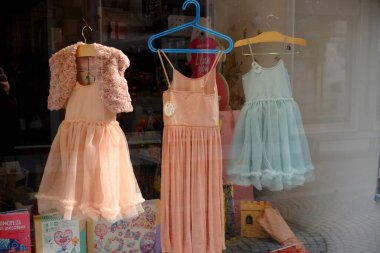 Lombardy, İtalya 1 Mart 2025 Üç zarif elbise, pembe omuz silkme, uzun şeftali rengi ve açık mavi bir elbise, Cremona, İtalya 'da bir mağaza vitrininde asılı.