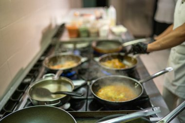 Profesyonel aşçılar, kalabalık bir lokanta mutfağında Hint yemekleri pişiriyor. İstekli müşteriler için lezzetli yemekler hazırlıyorlar.