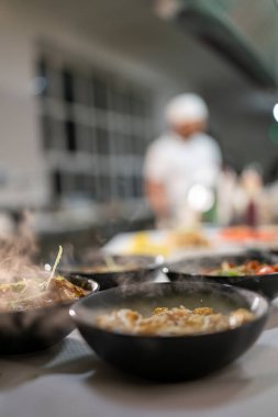 Hint restoranında siyah kaselerde servis edilen sıcak Hint yemekleri müşterileri zengin baharat ve aromalarla dolu leziz bir mutfak deneyimi yaşamaya davet ediyor.