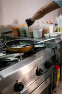 Profesyonel bir aşçı, restoranın mutfağında, profesyonel bir fırında Hint yemeği pişirirken siyah eldivenler giyer.