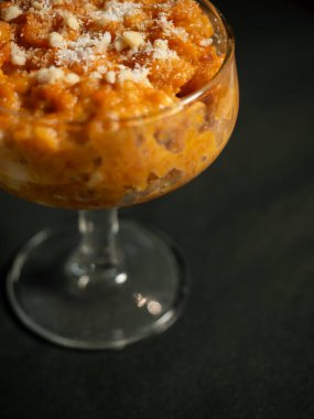 Gajar ka halwa, rendelenmiş havuç, süt, şeker ve fındık ile yapılan geleneksel bir Hint tatlısıdır, zarif bir bardakta servis edilir ve bir Hint restoranında görsel olarak çekici bir sunum oluşturur.