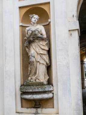 Colonno, İtalya 1 Mart 2025 'te, Colonno Düklüğü' nün duvarındaki bir oyukta, elinde çiçekler bulunan yıpranmış bir heykel tarihi mimariyi gözler önüne seriyor.