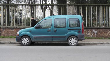 Bologna, İtalya 7 Şubat 2025 Teal Renault Kangoo I Faz II, kaldırımda yürüyen bir öğrenciyle bir caddenin kenarına park etti.
