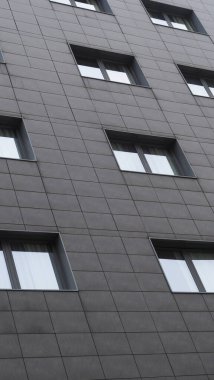 Bolonya, İtalya 7 Şubat 2025 Modern bir binanın ön cephesi koyu gri gökyüzünü yansıtan dikdörtgen pencereli, geometrik desenli