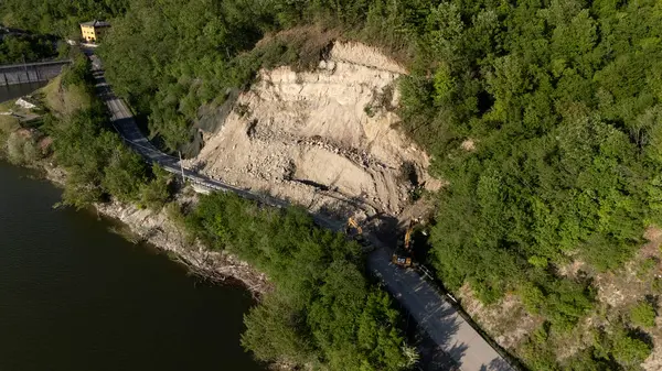 Mignano, İtalya - 22 Nisan 2025 Havadan çekilen ve Mignano Barajı 'nda engellenmiş SP21 Vernasca fotoğrafı, yol kenarında park halindeki kazıcılarla birlikte toprak kayması yaşıyor
