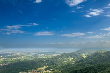Brosso, Val Chiusella, İtalya 'dan görülen İvrea Morainic Amfitiyatrosunun insansız hava aracı panoraması açık gökyüzü altında yemyeşil ovalar, ağaçlar ve dağınık köyler, yüksek drone atışları, yavaş çekim