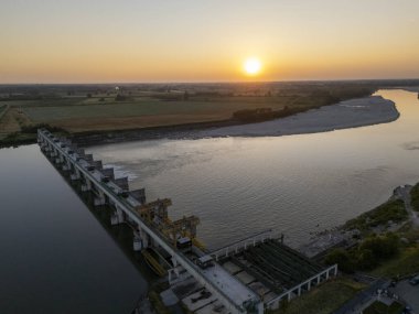 Carlo Bobbio 'nun Isola Serafini' deki havadan Piacenza ve Cremona arasındaki Po Nehri 'ndeki barajının günbatımında çekilen görüntüsü balık yolu projesinin akıntıya karşı mersin balığı göçüne olanak sağladığını gösteriyor..