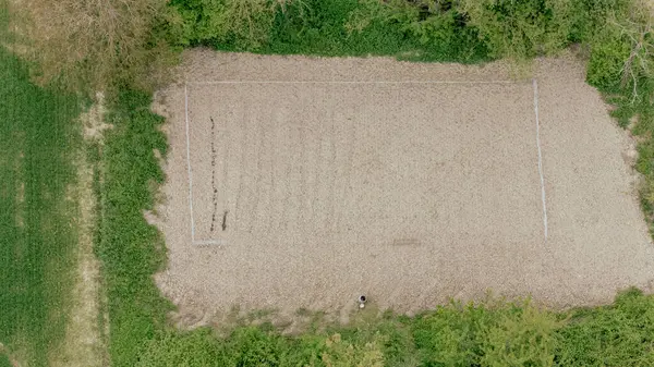 Yeşil bitki örtüsüyle çevrili yeni düzleştirilmiş dikdörtgen alanın havadan görünüşü, kırsal bölgenin ortasında görünen toprak izleri ve sıkıştırılmış toprak ile yeni bir sebze bahçesi için hazırlanıyor..