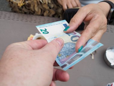 20 avroluk bir fatura transferi ile ilgili iki kişinin nakit ödemesi. Para transferi para birimi ve elleri çerçeve ekonomisinde görünür.