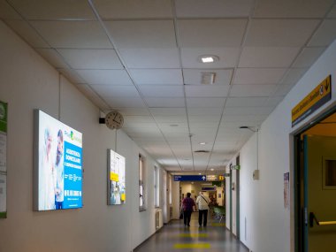 Cisanello, PI, İtalya - 13 Haziran 2025 hastane iç koridoru içinde tıbbi işaretler ve reklam panelleri bulunan hastalar ve personel ile çağdaş bir sağlık ortamı hissi yaratıyor