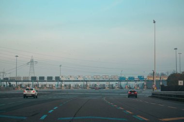 Milano, İtalya - 27 Aralık 2023 Milano otoyolunda gün boyunca açık mavi gökyüzü altında geçiş yapan araçların görüntüsü
