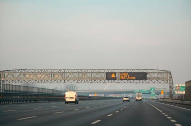 Milan, İtalya - 27 Aralık 2023 sisli bir günde Milano otoyolunda ilerleyen araçlar ve kamyonlar modern bir yol altyapısı ve ulaşım aracının çarpıcı bir görüntüsünü yaratıyor.