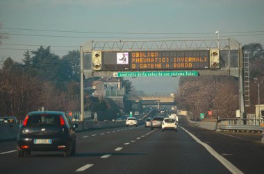 Milan, İtalya - 27 Aralık 2023 Milano otoyolunu kullanarak modern altyapı taşımacılığı araçları ve İtalyan manzarasının işaretlendiği yol boyunca İtalya 'ya yapılan pitoresk bir seyahat gerçekleştirdi.