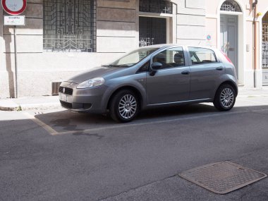 Cremona, İtalya 11 Haziran 2025 Gri Fiat Grande Punto 1.3 Multijet 5 kapılı araç asfalt bir şehir caddesinde belirlenmiş bir park yerini işgal ederek günlük şehir hayatının özünü yakalıyor.