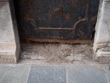 Paslı metal bir kapının altını kapatın. Altındaki zemin ve kaldırımı ortaya çıkarın. Şehrin çürüdüğünü ve Cremona, Lombardy, İtalya 'da zamanın nasıl geçtiğini gösterin.