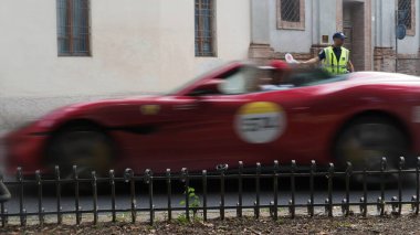 Cremona, İtalya 21 Haziran 2025 Klasik kırmızı Ferrari tarihi Cremona caddelerinde yarışıyor, hareket Mille Miglia klasik araba etkinliği sırasında bulanıklaşıyor, trafik polisi kavşağı kontrol ediyor