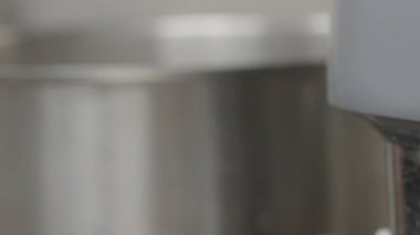 Soyut bir kompozisyon yaratmak, endüstriyel bir mutfakta bulanık metalik yüzeyler ışığı yansıtır, parlak gölgeler ve pürüzsüz, parlak dokular arasında gölgeler oluşturur.