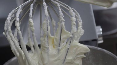 Tereyağlı krema çırpma profesyonel bir mutfak mikserinde kek malzemelerini karıştırdıktan sonra çırpma kabını kaplıyor, kremalı, pürüzsüz dokuları lezzetli tatlılar pişirmek için ideal.