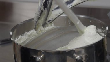 Profesyonel fırıncı spatulayla karıştırıcı krem sürerek spatulayla karıştırıyor, karışımın dokusunu yakın plan kek hazırlama sahnesinde yakalıyor.