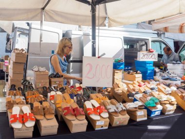 Cremona, İtalya. 28 Haziran 2025. Sokak satıcısı. Cremona, Lombardy, İtalya 'da bir açık market standında renkli deri sandaletler sergiliyor.