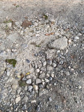 Kapalı bir araba yolu manzarası. Küçük taşlar ve enkaz parçaları yere saçılmış. Açık havada detaylı bir fotoğraf.