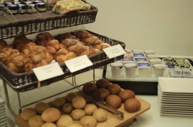 Taze pişmiş kruvasan, yoğurtlu ekmek ve sıcacık bir akşam yemeğinde reçel içeren çok güzel hazırlanmış bir büfe kahvaltısı.