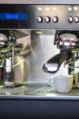 Cremona, İtalya - 19 Temmuz 2025 Profesyonel Espresso Makinesinin Yakın Çekimi Taze demlenmiş Kahveyi Paslanmaz Çelik Tezgahın Üzerinde Beyaz Seramik Kupa haline getiriyor