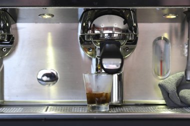 Cremona, İtalya - 21 Temmuz 2025 Profesyonel bir kahve makinesinden küçük bir cam fincana dökülen koyu espresso yakın plan çekimleri paslanmaz çelik tezgahta mükemmel bir sabah içeceği oluşturur