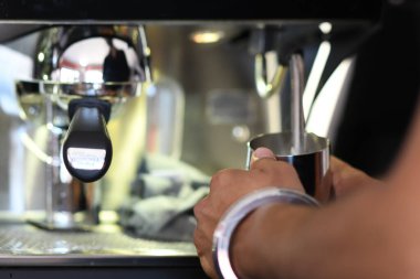 Cremona, İtalya - 21 Temmuz 2025 Modern bir kafe ortamında müşteriler için kahve makinesi hazırlayan bir espresso makinesiyle metal sütü dikkatlice buharlaştıran bir baristaya yaklaş