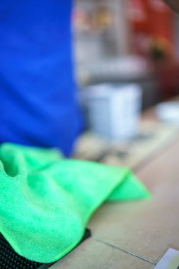 Bir insanın kolunu gösteren yeşil bir bezle deriyi delen iğnenin ucunu kapat ve bazı objelerle arka planı bulanıklaştır. Bu da bir prosedür veya tedavinin devam ettiğini gösteriyor.