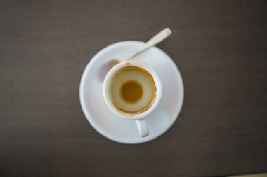 Koyu kahverengi ahşap bir masanın üstünde Kaşık ve Bisküvi ile nefis bir kahve fincanı.