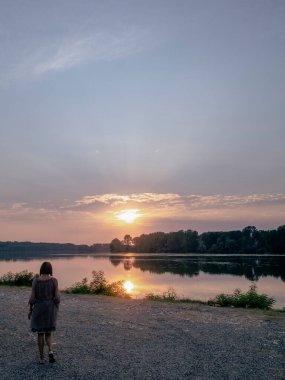 İtalya, Emilia Romagna 'da Po nehrinin kıyısında tek başına yürüyen bir kadın, doğanın güzelliği ile çevrili huzurlu bir anın tadını çıkarıyor.