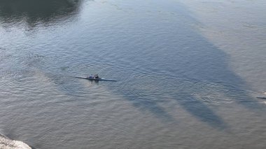 Cremona, İtalya 2 Haziran 2025 'te Po Nehri' nde kürek çeken iki sporcu, Emilia Romagna ve Lombardy arasında antrenman yaparak, su yüzeyinde iz bırakıyor ve gölgeleri nehre yansıtılıyor.