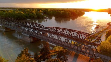 İtalya 'nın Cremona kentindeki canlı bir günbatımında Po Nehri' ne yayılan Demir Köprü 'yü, bir yol ve demiryolu viyaoluğunu ele geçiren İHA, çevresindeki yemyeşil araziyi ve sakin suları gözler önüne seriyor.