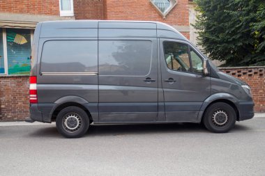 Cremona, İtalya 6 Ağustos 2025 Gri bir Mercedes Benz Sprinter minibüsü sokakta tuğla bir binanın önünde park halinde.