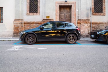Cremona, İtalya 6 Ağustos 2025 Modern siyah Mercedes Benz GLA bir şehir sokağındaki belirlenmiş park yerine doğru park etmiş, gösterişli tasarımı ve şehir manzarasına entegrasyonunu sergiliyor.